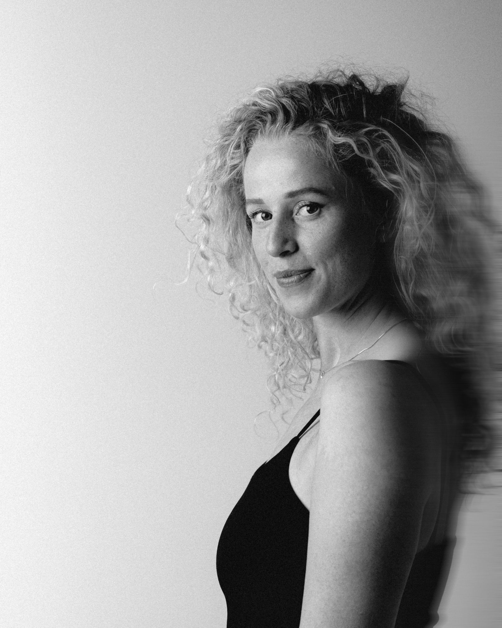 Zwart-witportret van Evelynn die over haar schouder in de camera kijkt